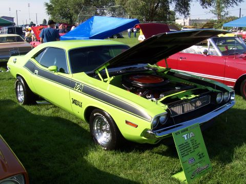 1973 Ford Mustang - A lime green 1970 Dodge Challenger T/A is displayed with its hood open, the engine and a descriptive placard.
