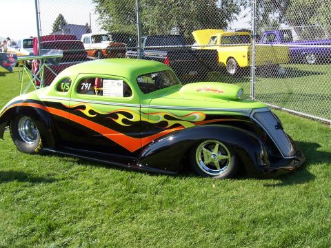 1973 Ford Mustang - Custom hot rod with flames parked on grass, with other vehicles in the background.