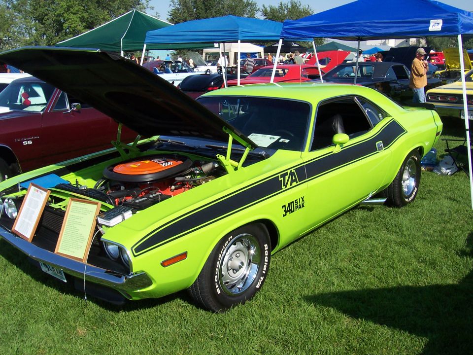 Lime green 1970 Dodge Challenger T/A with black stripes, hood open, parked on grass