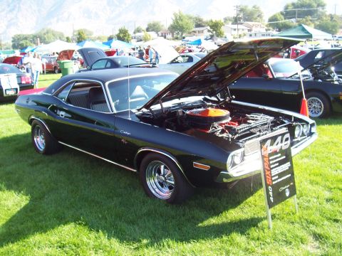 1973 Ford Mustang - A black Dodge Challenger R/T is displayed with its hood open at an outdoor car show.