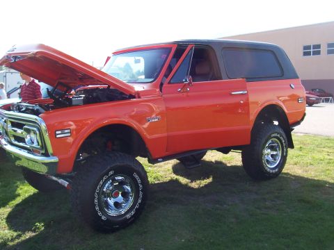 1973 Ford Mustang - This lifted SUV, likely from the early 1970s, is parked on grass with its hood and driver's door open.