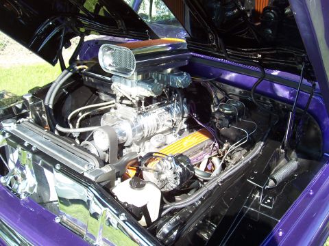 1973 Ford Mustang - Customized engine bay features a prominent chrome supercharger and vibrant purple paintwork.