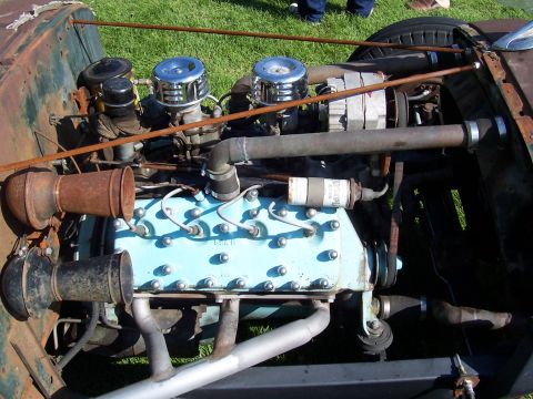1973 Ford Mustang - The engine bay of a vintage vehicle features an inline-six engine with custom air intakes and exhaust headers.