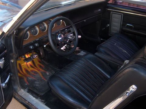1971 Mercury Cyclone - The interior of a car shows black vinyl seats and a dashboard with round gauges.