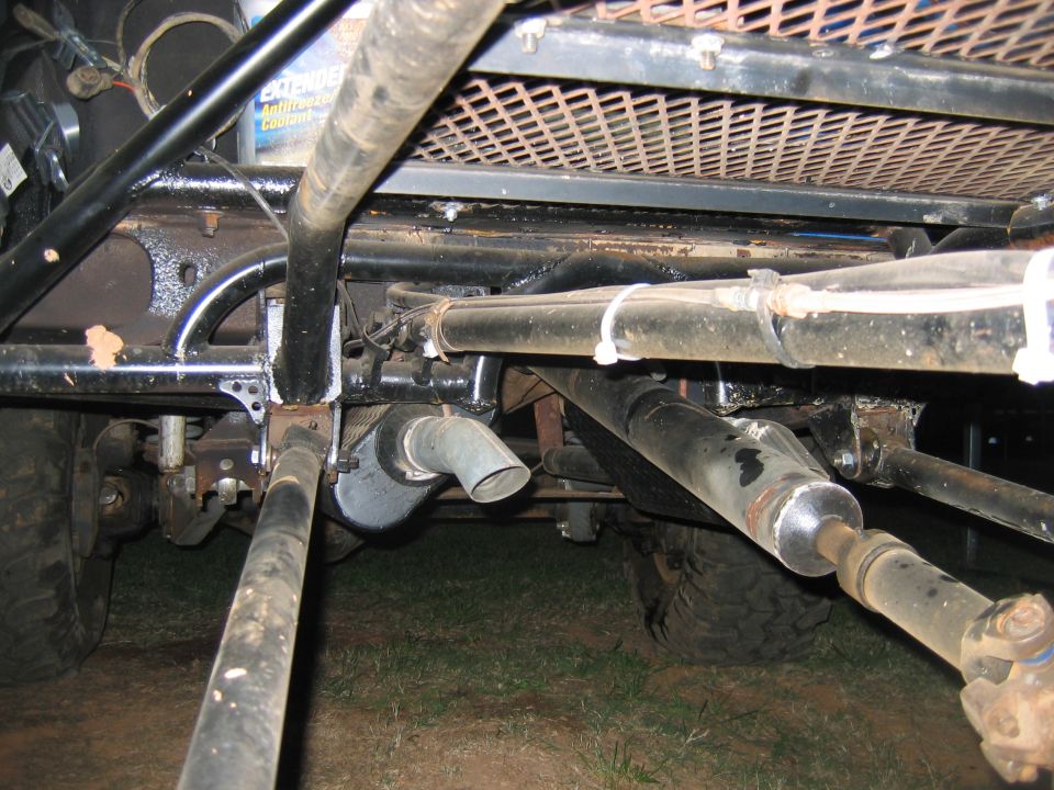 Undercarriage of a modified off-road vehicle with exposed drive shafts, exhaust pipe, and roll cage