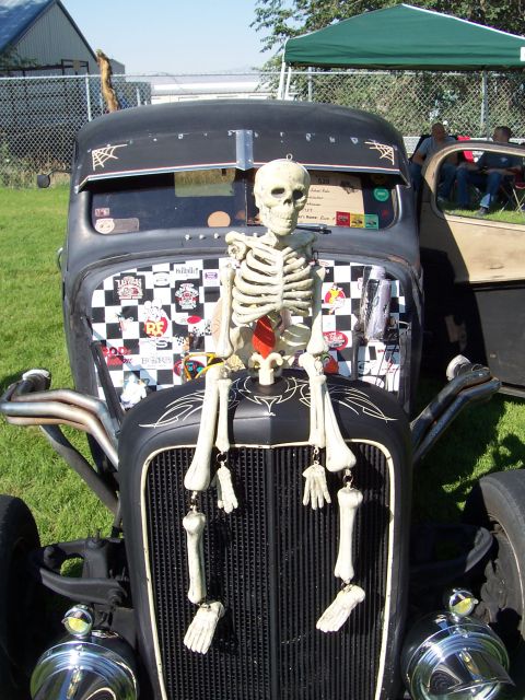 1973 Ford Mustang - A skeleton decoration is placed on the hood of a black hot rod with custom paint and stickers.