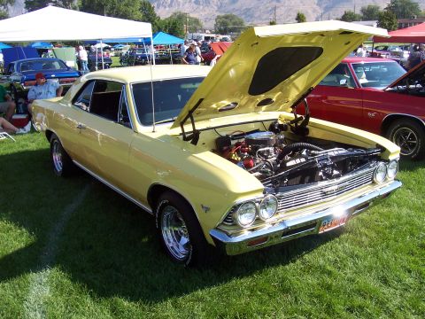 1973 Ford Mustang - A yellow 1966 Chevrolet Chevelle coupe is displayed with its hood open at an outdoor car show.