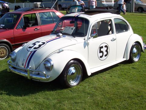 1973 Ford Mustang - Herbie the Love Bug, a 1967 Volkswagen Beetle, is parked on grass next to a red car.