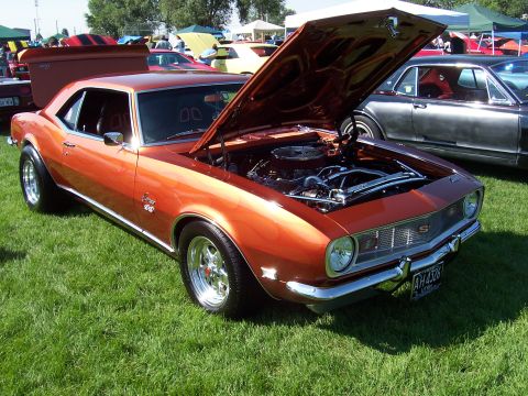 1973 Ford Mustang - This orange 1967 Chevrolet Camaro SS is displayed with its hood open at an outdoor car show.