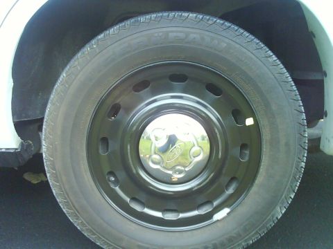 2003 Ford Crown Victoria - A close-up shot focuses on the wheel and tire assembly of a vehicle, a Ford logo on the hubcap.