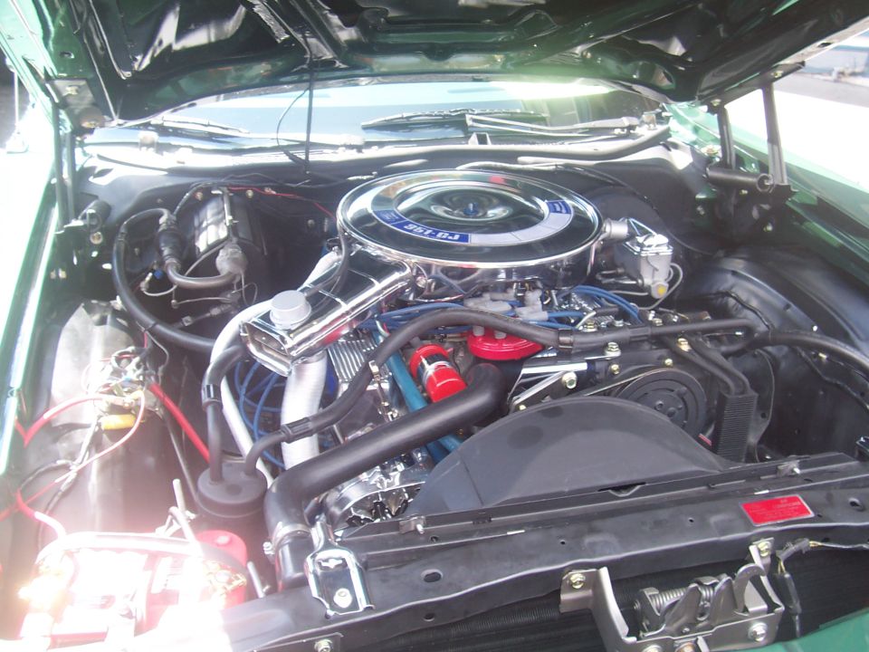 Engine bay of a 1972 Ford Ranchero with a 351 V8 engine, chrome air cleaner, and blue spark plug wires