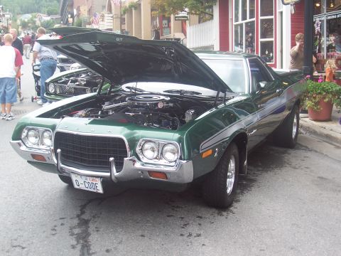 1972 Ford Ranchero - A green Ford Ranchero GT is parked on the street with its hood open, revealing the engine.