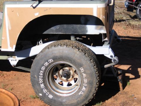 1980 Jeep CJ7 - A Jeep's side fender is covered in cardboard, revealing a radial tire and steel wheel.