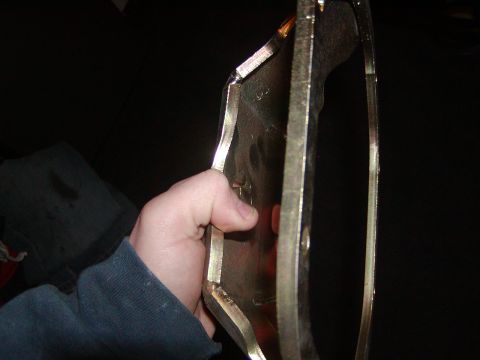 1991 Ford Bronco - A hand holds a metal component, possibly from a vehicle, in front of a dark background.