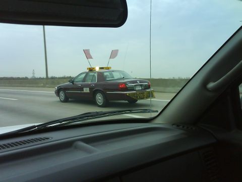 2003 Ford Crown Victoria - This 2003 Ford Crown Victoria is driving on the highway with an oversized load sign and flags.