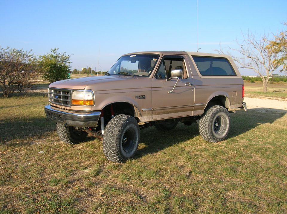 Lifted brown 1996 Ford Bronco parked on grassy terrain