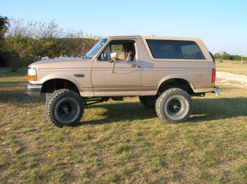 1996 Ford Bronco - Side view of a lifted 1996 Ford Bronco SUV with aftermarket wheels and tires.