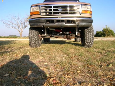 1996 Ford Bronco - This lifted 1996 Ford Bronco features a prominent Ford badge on its grille and aggressive off-road tires.