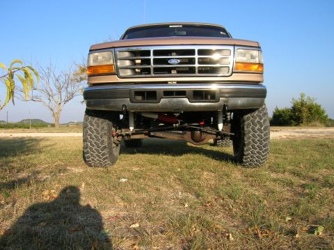 1996 Ford Bronco - Front view of a lifted 1996 Ford Bronco with large off-road tires and clear blue sky.
