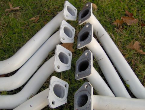 1978 Ford Bronco - Pair of white exhaust headers laid out on grass, showing their flange ports.
