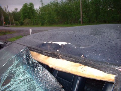 1996 Ford Crown Victoria - The vehicle's roof has a large dent and the windshield is broken, revealing the interior.