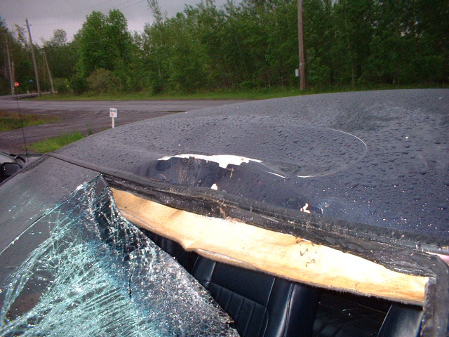 car roof is dented and windshield is shattered, showing interior and damaged headliner