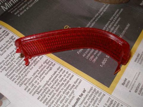 2001 Ford Crown Victoria - Red plastic automotive reflector shown on top of printed newspapers.
