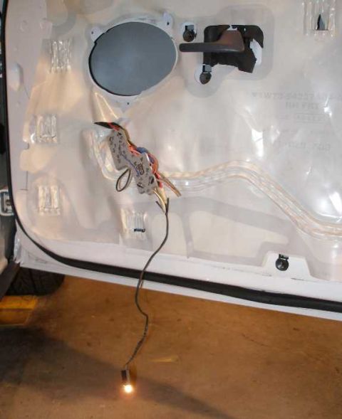 2001 Ford Crown Victoria - Interior of a car door panel showing wiring and a light bulb hanging down.