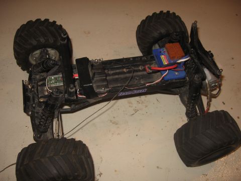 1979 Ford Bronco - The underside of a remote control monster truck is shown with its internal components visible.