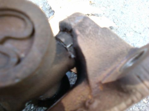 1995 Ford Bronco - Close-up of a worn driveshaft universal joint, showing signs of rust and damage.
