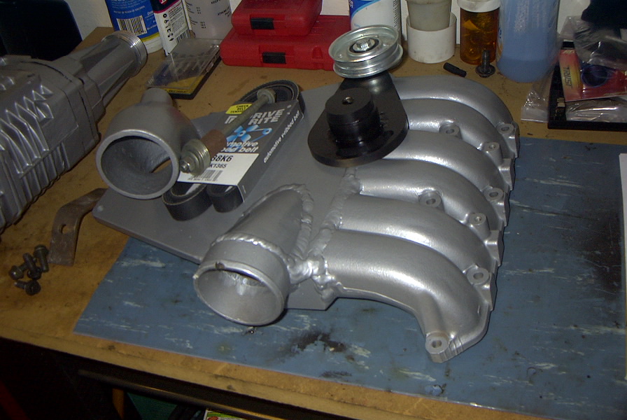 Silver painted intake manifold with pulley on a workbench