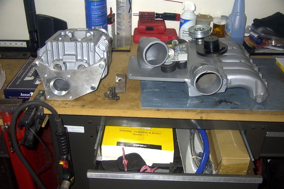 Supercharger components on a workbench with a yellow service manual