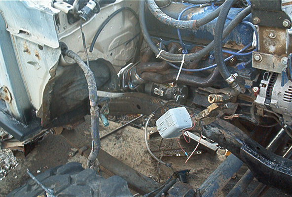 Engine bay of vehicle with frame partially stripped showing wiring, alternator and master cylinder