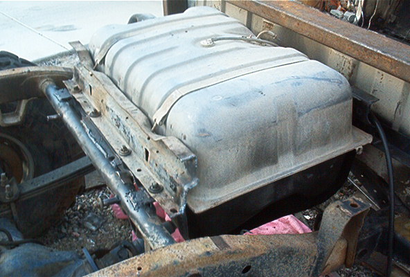 Fuel tank mounted on rusty chassis components, viewed from the side