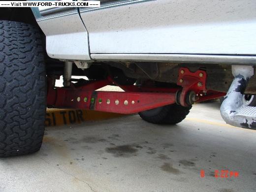 Close-up of red aftermarket suspension components on a truck, with a large tire visible