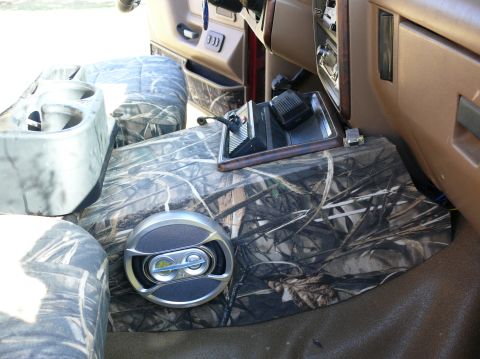 1988 Ford Bronco - The interior of a vehicle is shown with camouflage seat covers and floor mats, along with a speaker and center console.