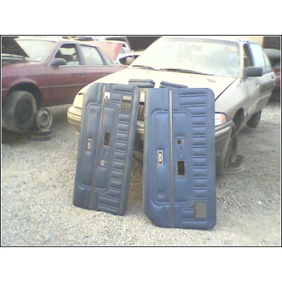 1973 Ford Ranchero - Two blue interior door panels are displayed in front of a weathered vehicle at a junkyard.