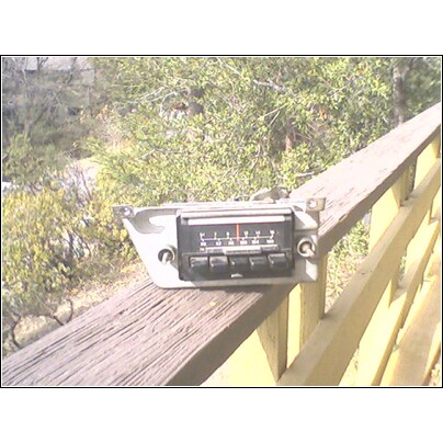 1972 Ford Ranchero - A car radio is resting on a wooden railing outdoors.