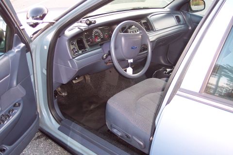 2001 Ford Crown Victoria - The interior of a 2001 Ford Crown Victoria, the dashboard, steering wheel, and driver's seat with visible controls.