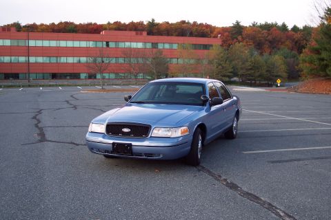 2001 Ford Crown Victoria - A blue 2001 Ford Crown Victoria is parked in a lot during autumn.