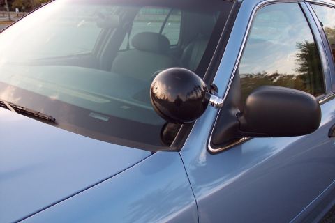 2001 Ford Crown Victoria - Close-up of a police car's front passenger side, highlighting its spotlight and side mirror.