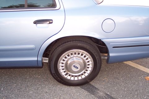 2001 Ford Crown Victoria - Rear side view of a light blue 2001 Ford Crown Victoria, showing the wheel and quarter panel.