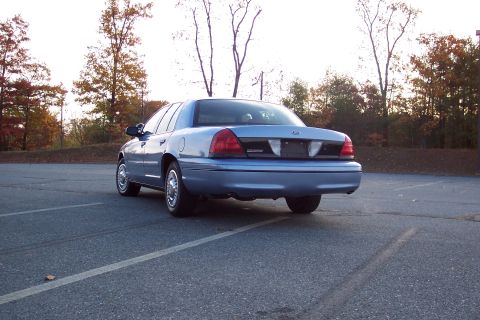 2001 Ford Crown Victoria - Rear view of a blue 2001 Ford Crown Victoria parked in a lot during autumn.