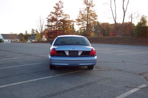 2001 Ford Crown Victoria - Rear view of a blue 2001 Ford Crown Victoria parked in an empty lot during autumn.