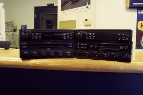 2001 Ford Crown Victoria - Two car radios are displayed on a counter, likely for sale or comparison.