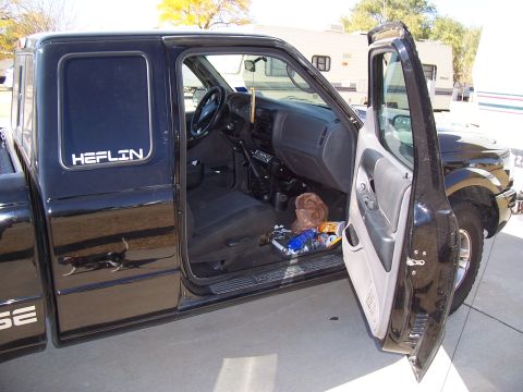 2003 Ford Ranger - The interior of a black Ford Ranger pickup truck is visible with the driver's side door open.
