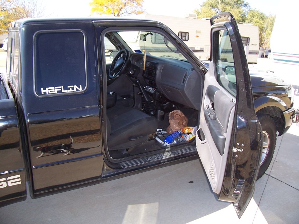Black Ford Ranger with driver's door open, showing interior and 'HEFLIN' decal on the rear door