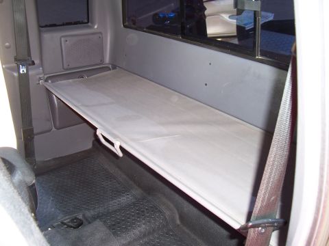 2003 Ford Ranger - Fold-down shelf installed in the rear of a truck cab, above the floor mats.