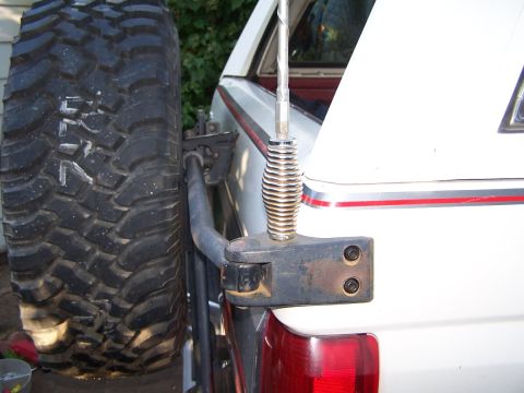 1990 Ford Bronco - Close-up of a spare tire and antenna mount on the rear of a white vehicle.