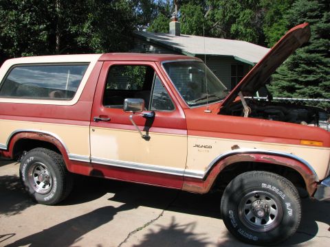 1986 Ford Bronco - This 1986 Ford Bronco is shown in a 3/4 front view with its hood raised, revealing the engine bay.